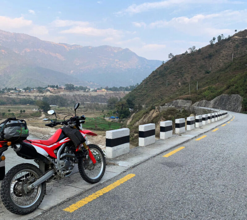 Honda CRF250 dual-sport motorcycle riding on a mountain road of Nepal.