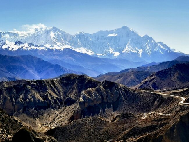 The breathtaking landscape of Upper Mustang highlights its arid valleys, rugged mountain formations, and remote dirt roads.