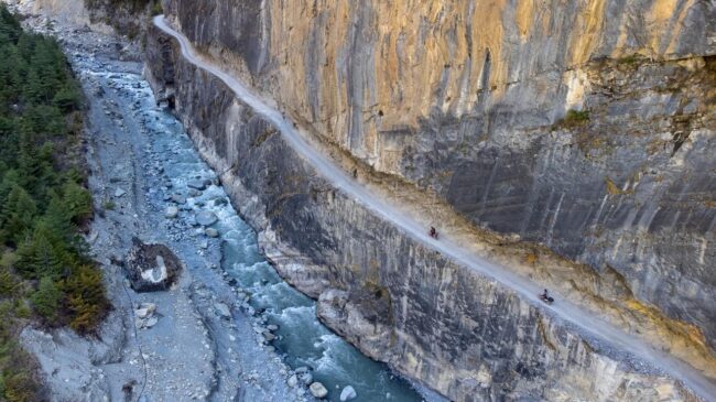 Nepal Manang Motorcycle adventure, riding along a narrow mountain trail with steep drops on the sides.