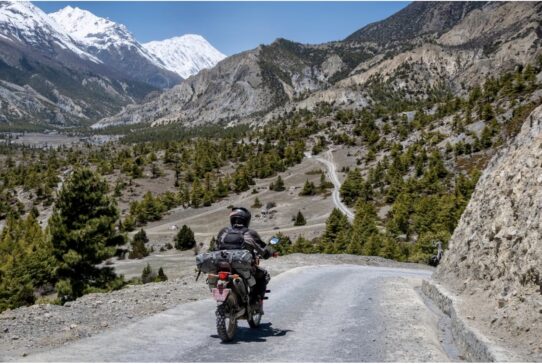 Adventure rider on a motorcycle tour in the high Himalayas mountain road in Nepal