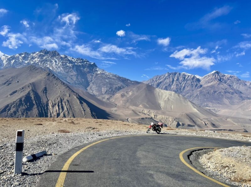 Honda dual-sport motorcycle on a Himalayan trail with mountains surrounding the route to Muktinath, Nepal.